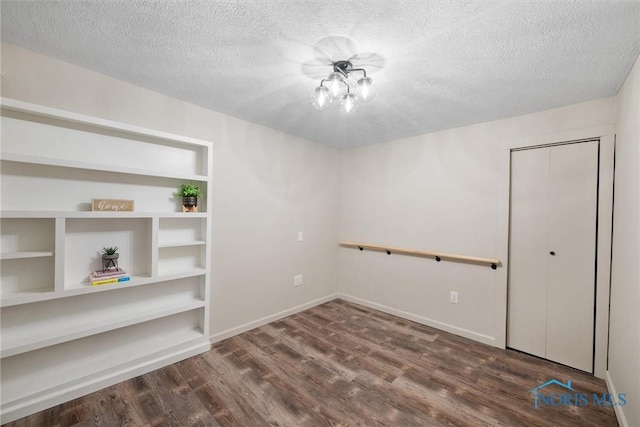 unfurnished room featuring a textured ceiling, baseboards, and wood finished floors