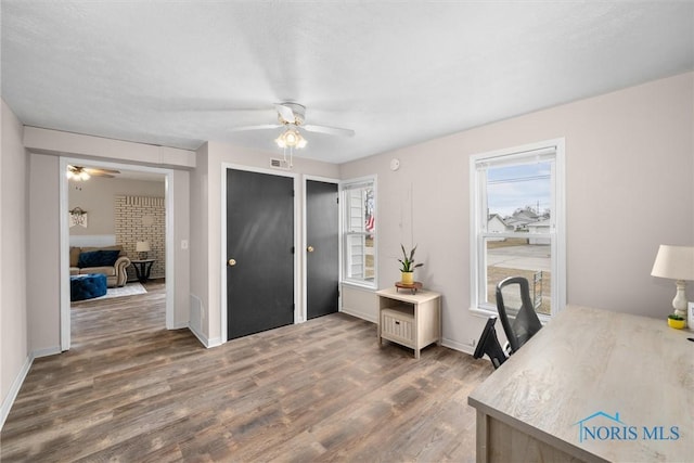 office featuring visible vents, ceiling fan, baseboards, and wood finished floors