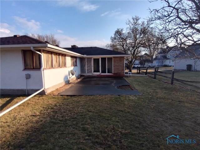 rear view of property with a patio, a yard, fence, and stucco siding