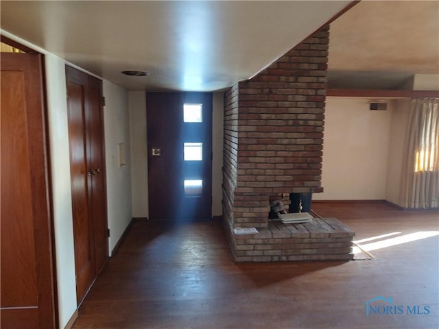 entrance foyer featuring a healthy amount of sunlight, a brick fireplace, visible vents, and wood finished floors