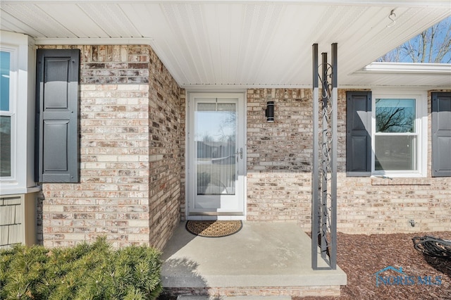 view of exterior entry featuring brick siding