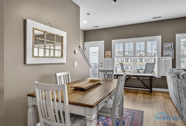 dining area with baseboards, visible vents, and wood finished floors