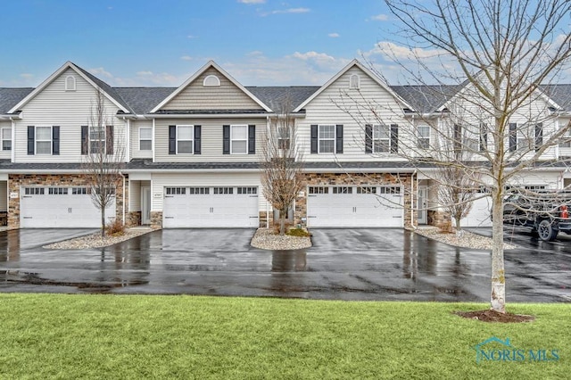 view of property with a front yard, stone siding, and driveway