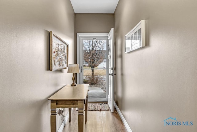 doorway to outside with baseboards and wood finished floors