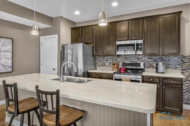 kitchen with hanging light fixtures, appliances with stainless steel finishes, backsplash, and dark brown cabinetry