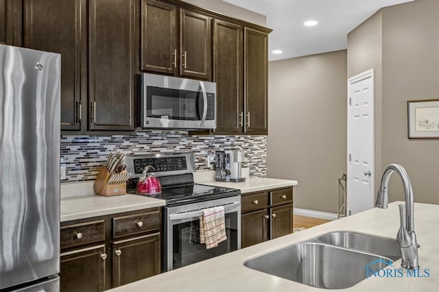 kitchen with decorative backsplash, stainless steel appliances, dark brown cabinets, light countertops, and a sink