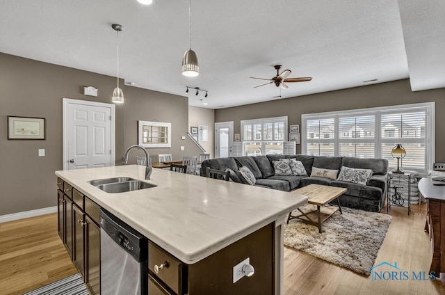 kitchen with dark brown cabinetry, a sink, light wood finished floors, and dishwasher