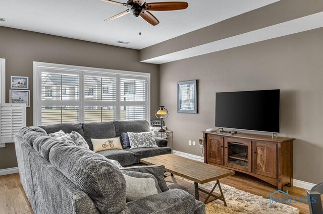 living area featuring baseboards, visible vents, and light wood finished floors