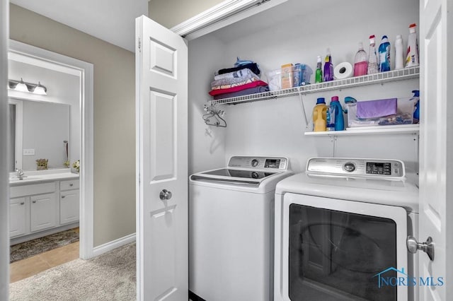 clothes washing area with washer and clothes dryer, light colored carpet, a sink, laundry area, and baseboards