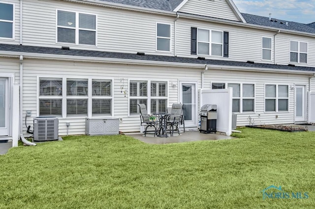 rear view of house with a shingled roof, a yard, a patio, and central air condition unit