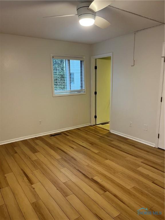 empty room with visible vents, ceiling fan, light wood-style flooring, and baseboards