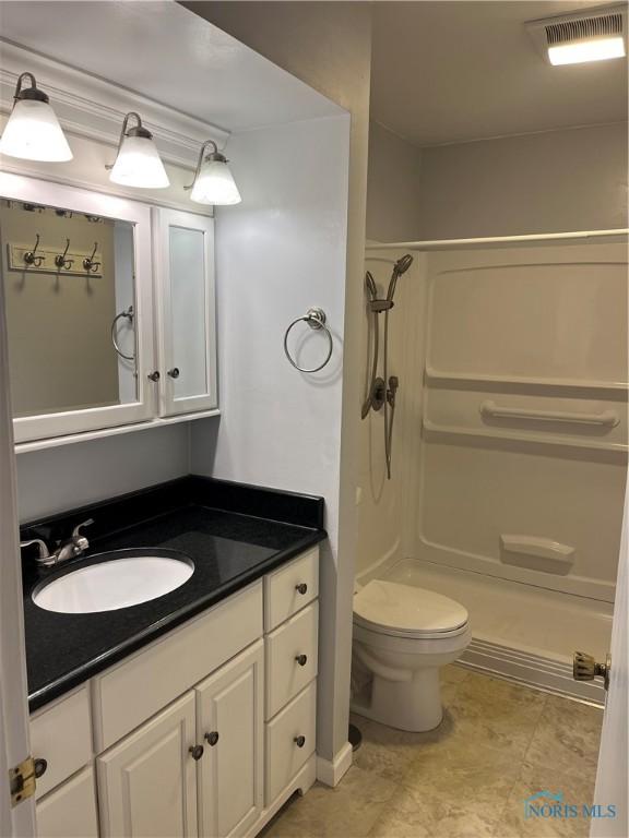 full bath with visible vents, a stall shower, vanity, and toilet