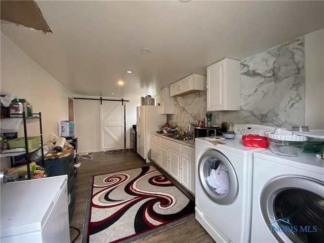 laundry room with a barn door, laundry area, a sink, independent washer and dryer, and dark wood-style floors