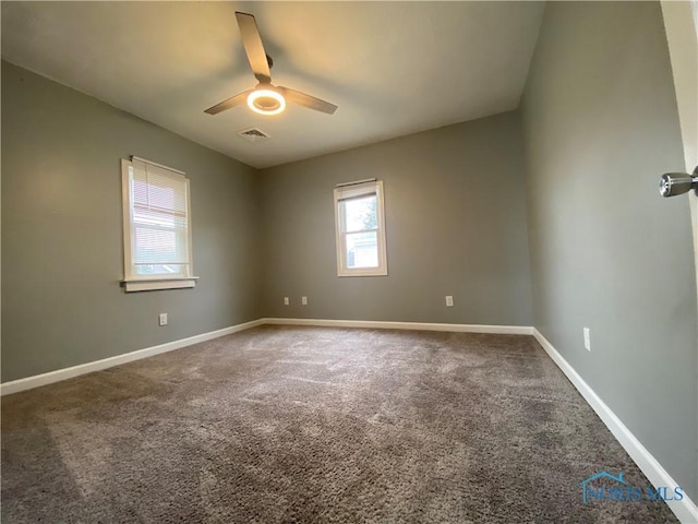 carpeted spare room with baseboards, visible vents, and a ceiling fan