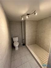 full bathroom featuring a stall shower, toilet, and tile patterned floors