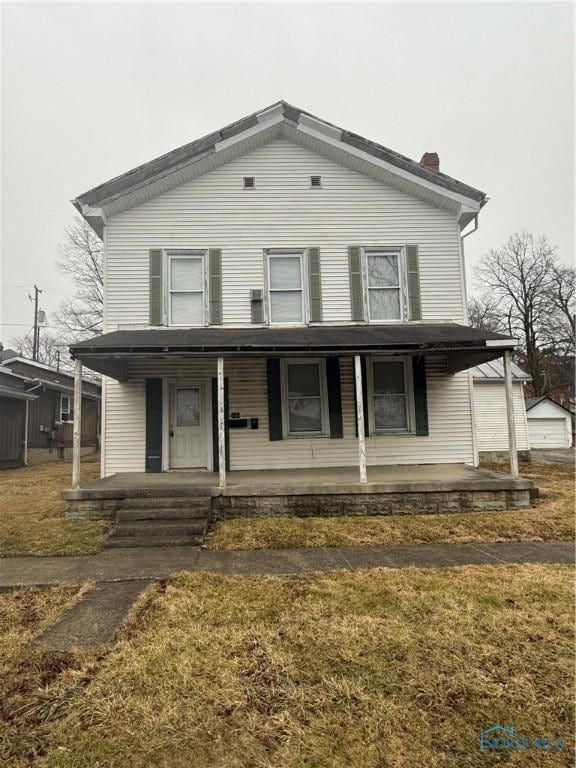 view of front of house featuring a chimney, a porch, and a front yard