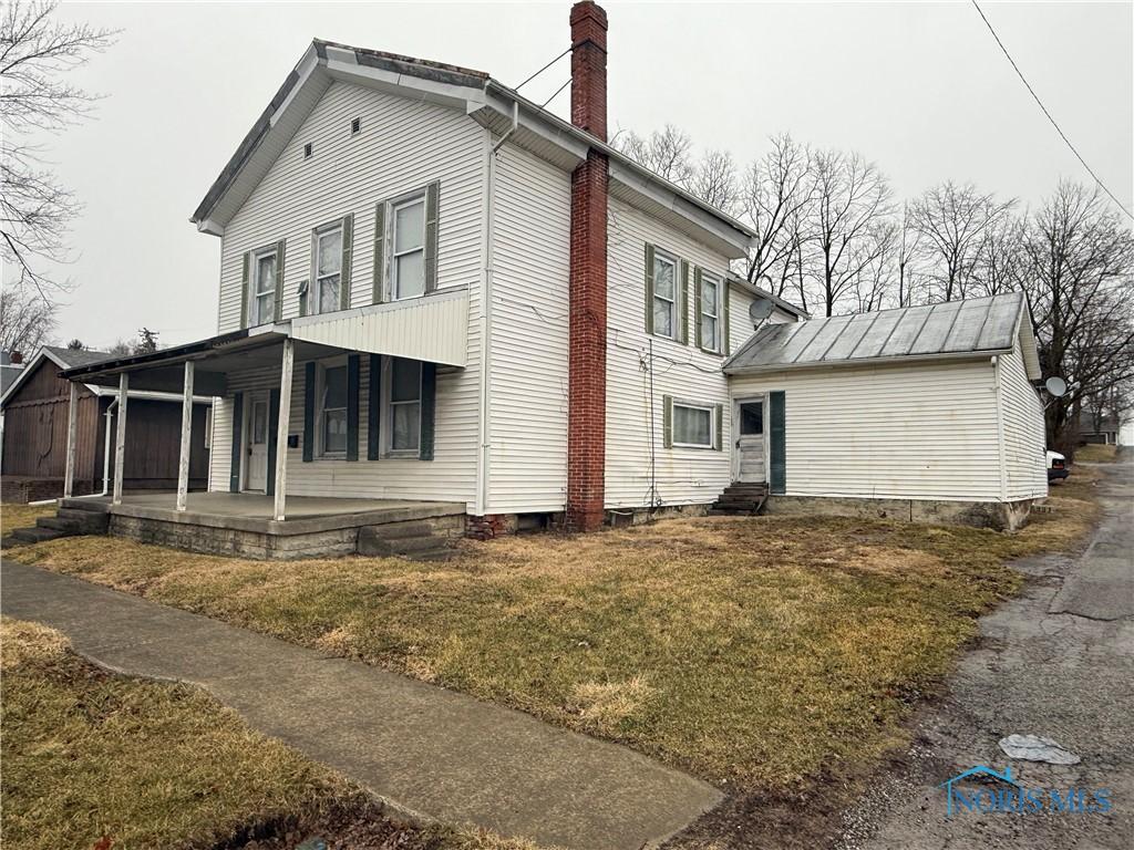 view of side of property with entry steps, a chimney, a patio, and a yard