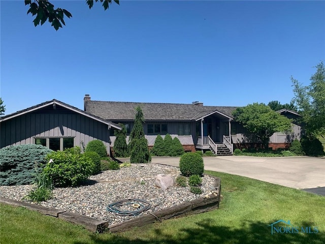 view of front of house featuring a front lawn, a chimney, and board and batten siding