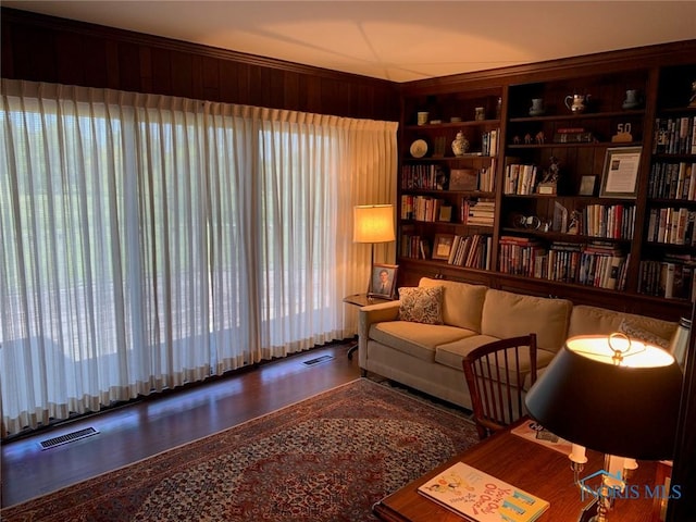 sitting room featuring built in shelves, visible vents, and wooden walls