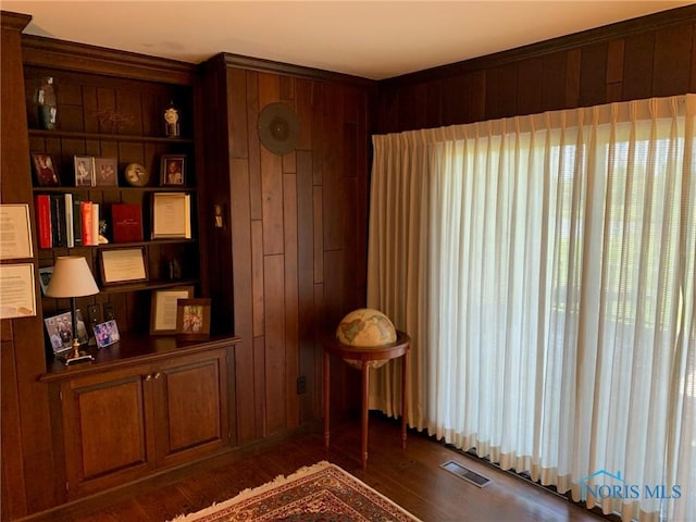 living area featuring wood walls, wood finished floors, and visible vents