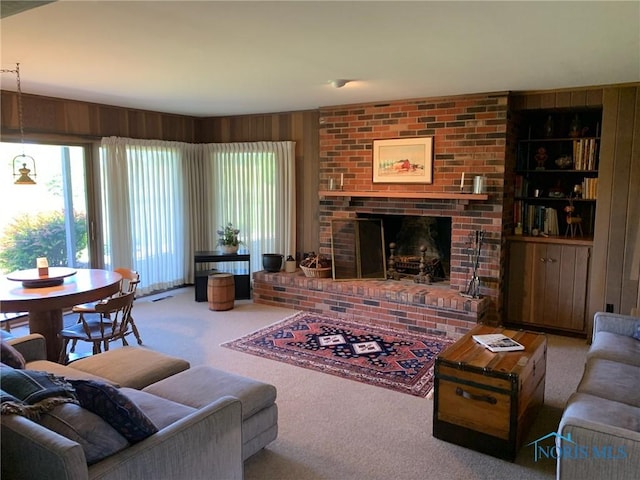 living room with carpet floors, wood walls, a brick fireplace, and visible vents