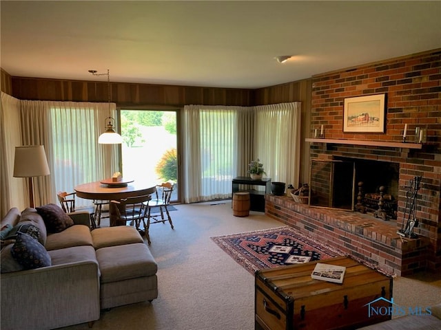 living area with a brick fireplace, carpet flooring, and wood walls