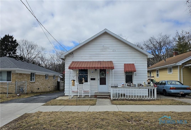 bungalow featuring covered porch, driveway, and fence