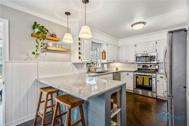 kitchen with a peninsula, white cabinets, appliances with stainless steel finishes, open shelves, and crown molding