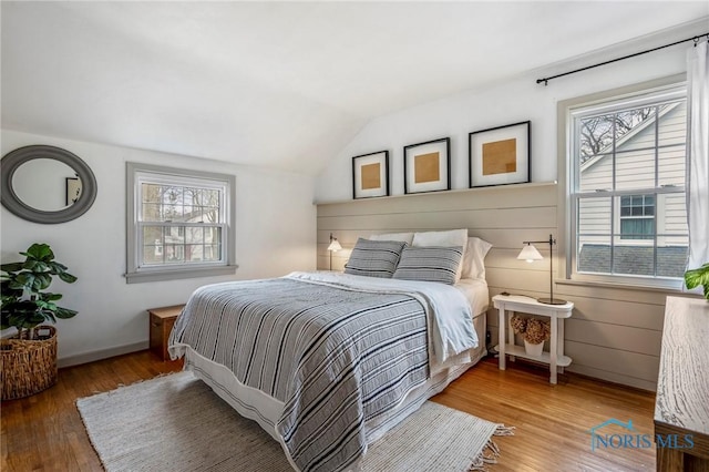 bedroom with lofted ceiling, multiple windows, and wood finished floors