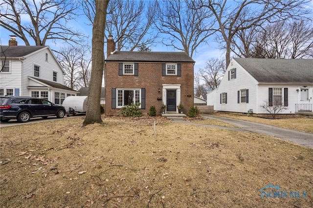 colonial-style house with a chimney and brick siding