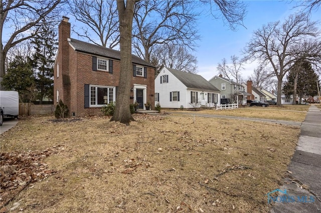 colonial inspired home featuring brick siding and a chimney