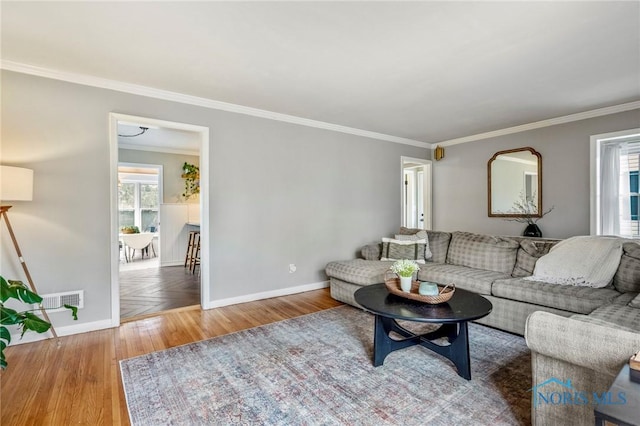 living room with visible vents, baseboards, wood finished floors, and ornamental molding