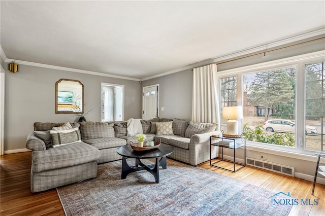 living area featuring visible vents, crown molding, baseboards, and wood finished floors