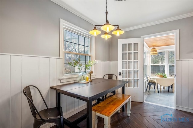 dining room featuring ornamental molding, a wainscoted wall, and an inviting chandelier