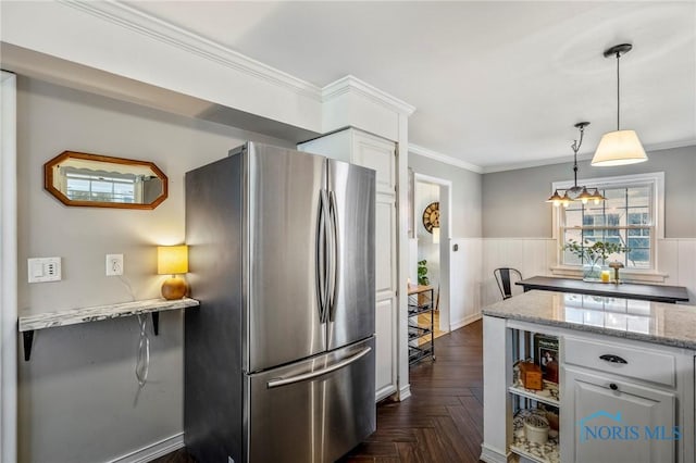 kitchen with light stone counters, freestanding refrigerator, white cabinets, and crown molding