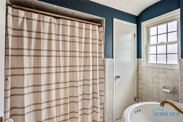 bathroom with a shower with shower curtain and tile walls