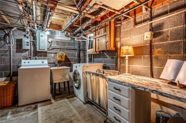 clothes washing area with washing machine and dryer, laundry area, electric panel, and a sink