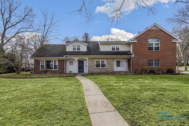 traditional-style house with stone siding, a shingled roof, brick siding, and a front yard