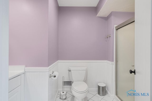 bathroom featuring tile patterned flooring, toilet, visible vents, wainscoting, and a shower stall