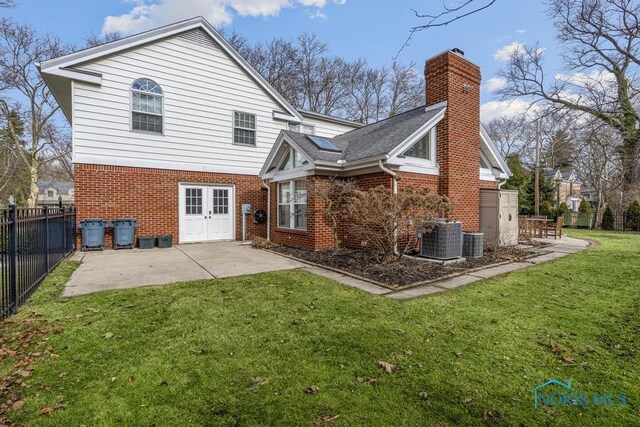 back of house featuring a yard, a chimney, a patio, and brick siding