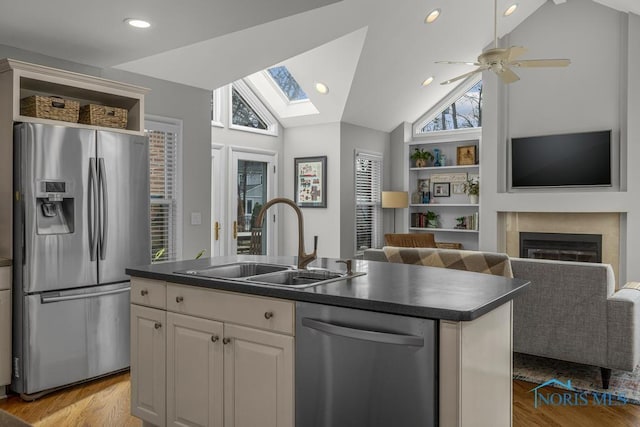 kitchen with dark countertops, stainless steel appliances, a sink, and open floor plan