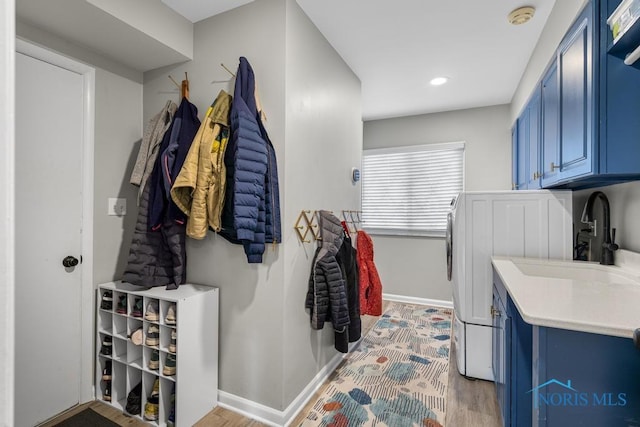 laundry area featuring cabinet space, light wood-style floors, a sink, independent washer and dryer, and baseboards