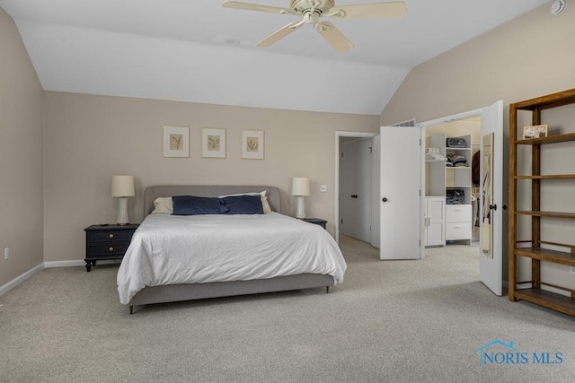 bedroom with a walk in closet, light colored carpet, vaulted ceiling, and baseboards