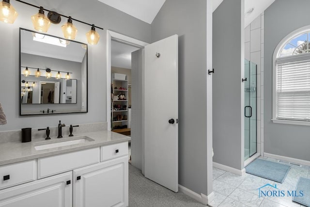 bathroom with lofted ceiling, vanity, baseboards, a shower stall, and a walk in closet