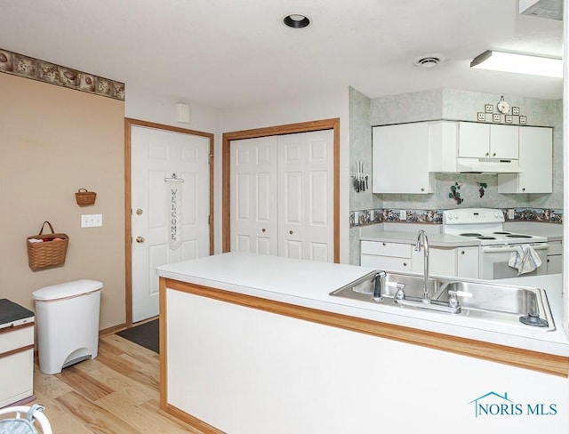 kitchen with under cabinet range hood, a sink, visible vents, white cabinets, and electric stove