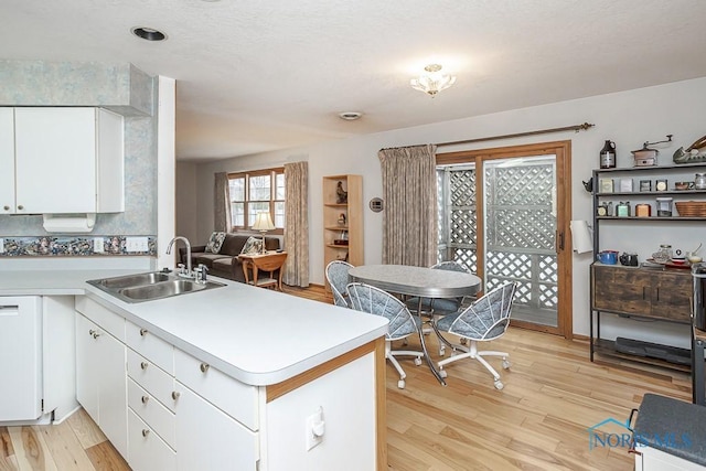 kitchen featuring a peninsula, light wood-type flooring, a sink, and light countertops