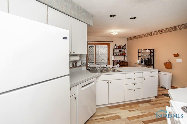 kitchen with white appliances, white cabinets, a sink, and a peninsula