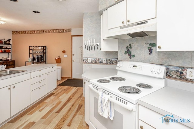 kitchen with decorative backsplash, light wood-style floors, electric stove, under cabinet range hood, and a sink