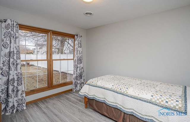 bedroom featuring light wood-style flooring, visible vents, and baseboards