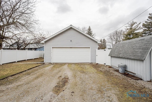 garage with dirt driveway and fence